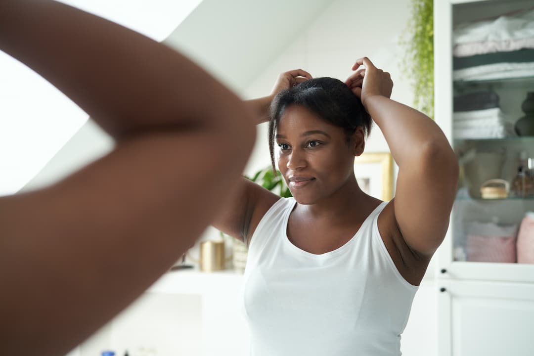 Femme qui regarde ses cheveux avant d'appliquer son shampooing antipelliculaire dans la salle de bain