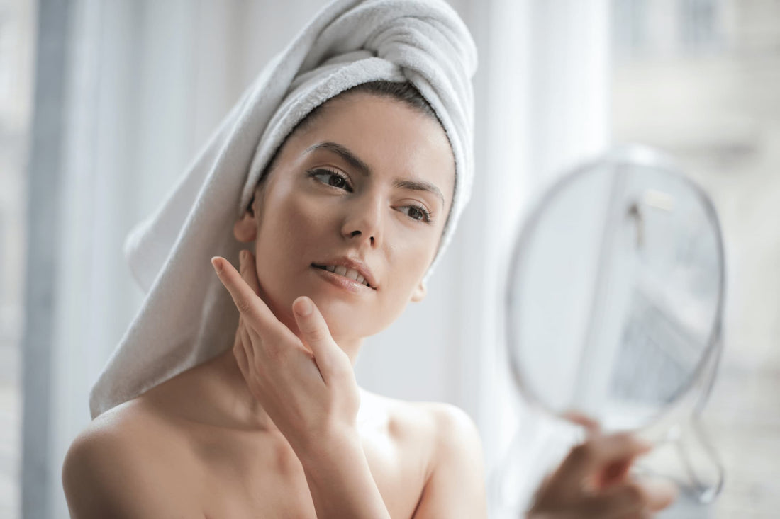 Femme avec serviette microfibre sur la tête se regarde dans un miroir 
